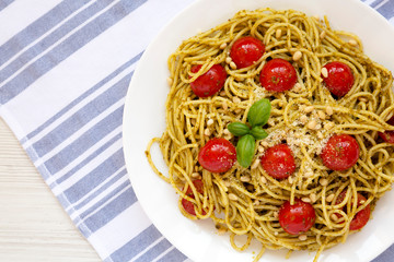 Homemade Pesto Pasta with Tomatoes and Pine Nuts on a white plate, top view. Flat lay, overhead,...