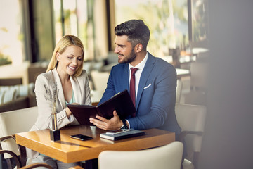 Happy business colleagues reading menu in a restaurant.