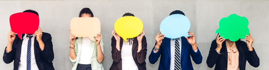 Group of business people holding a empty copyspace speech bubble icon while standing against grey...