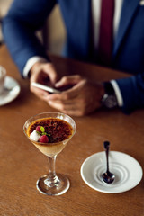 Lemon tart with raspberry sorbe in martini glass with businessman in the background.