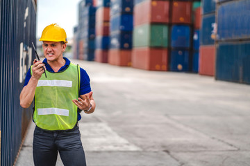 Professional engineer container cargo foreman in helmets working standing and using walkie talkie checking stock into container for loading.logistic and business export