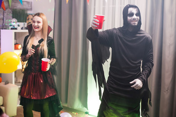 Man dressed up like a spooky grim reaper at a halloween celebration with his friends.