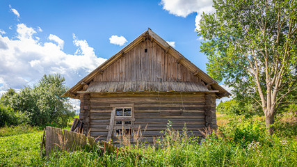 Collapsed house in a village on a sunny day with a downed fence