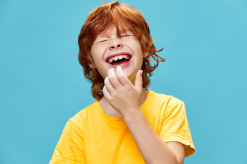 Happy boy with narrowed eyes laughs on a blue background