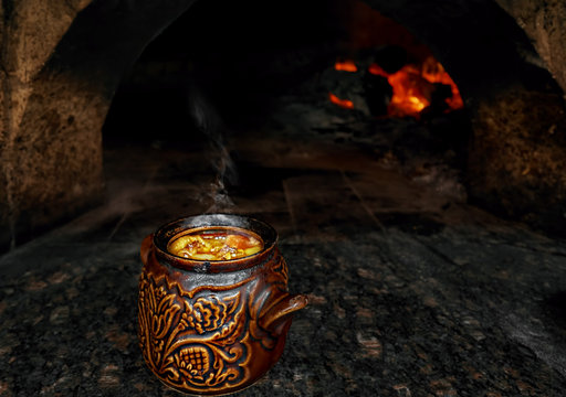 Cooking traditional baked soup in a clay pot in the hearth, over an open fire in a cafe. Lamb guvech with vegetables in a Turkish cafe