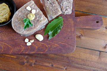  Home jelly, cut into portions lying on the kitchen Board.Near mustard, garlic, Bay leaf, parsley. Place for text. Top view.