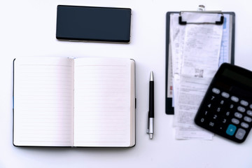 Office work table with bill, mobile phone, notebook and calculator on white table , Top view, copy space for text message