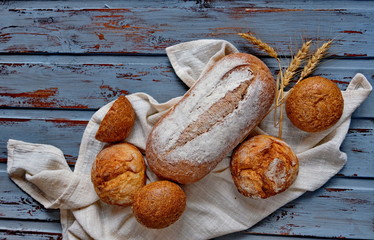 Freshly baked bread and wheat ears on a white towel lies on a blue wooden table top, a bakery and a...