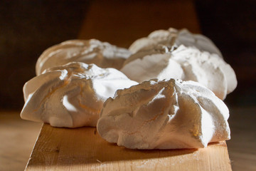 Off white marshmallow roses on wooden surface. Delicious homemade meringue cakes. The concept of home cooking of food.