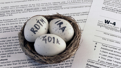 Conceptual composition. Pension savings. Individual retirement account. Three eggs with the inscriptions IRA, 401k, Roth lie in the nest against the background of the W-4 form. Close-up