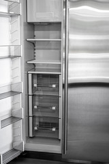 Open empty white refrigerator. Side View of Stainless Steel Double Door Refrigerator. Modern Kitchen and Domestic Household Appliances. 