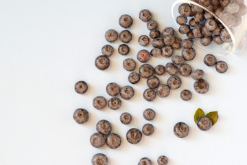 Fresh blueberries spilled out of the transparent bowl. Fresh blueberries on blue table. Concept for healthy eating and nutrition. Top view. Copy space.