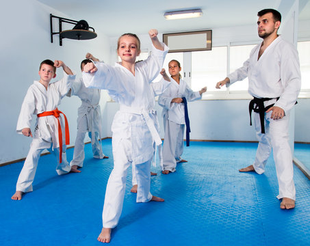 Teenagers are trying new techinque by repeating for the trainer in karate class.