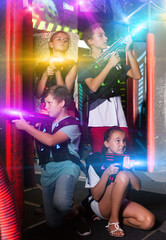 Portrait of excited teen kids with laser guns during lasertag game in dark room..