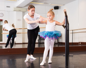 Fototapeta na wymiar Young female choreographer and little girl in classical dance school