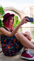 Caucasian woman a tourist takes a selfie under the Old Bridge, Mostar, Bosnia and Herzegovina.