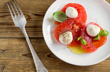 Caprese salad with ripe tomatoes and mozzarella with fresh Basil leaves.