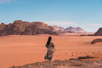 Fototapeta na wymiar Young Asian traveller with local Arab dress standing on top of mountain and enjoying landscape of Wadi Rum desert, Jordan, Arab