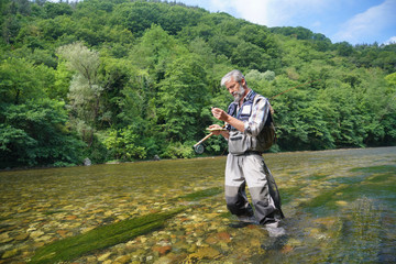 Man fly fishing in the summer in a beautiful river with clear water