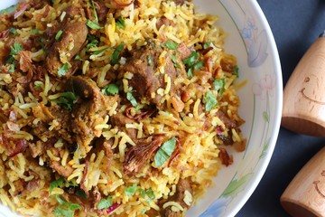 Mutton Biryani or Lamb Pulao. Garnished with fried onion & chopped coriander. Biryani is a famous Spicy non vegetarian dish of India. Goat meat cooked along with Basmati rice & spices.
