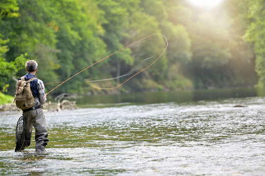 Man fly fishing in the summer in a beautiful river with clear water
