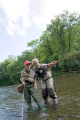 A father and his son fly fishing in summer on a beautiful trout river with clear water