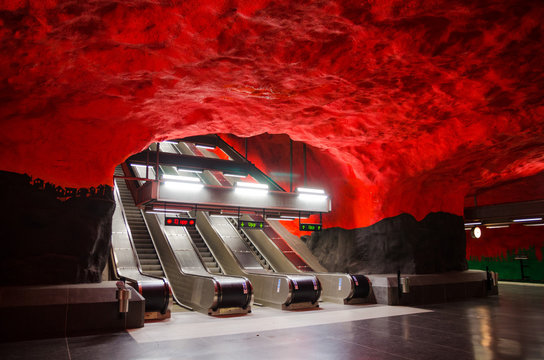 Sweden, Stockholm, May 30, 2018: underground metro tunnelbana station Solna Centrum (blue line, central station) with escalator and black red like fire caves walls and ceiling - modern art gallery