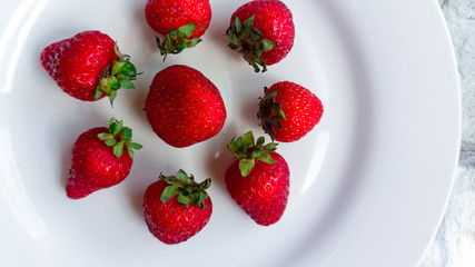 Strawberries on a white plate and white plate. Selective focus