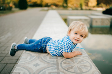 Picture of little caucasian boy in blue summer clothes walks to the park in summer