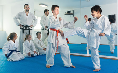 Fototapeta na wymiar Pair of children trying in sparring to use new technique at karate class
