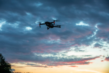 Flying drone quadcopter in the sunset cloudy sky