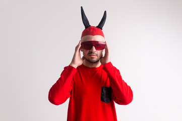 Strange devilish man in sunglasses and black red halloween costume posing over white background.