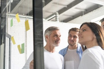 Business people meeting at office and use post it notes to share idea. Brainstorming concept. Sticky note on glass wall.