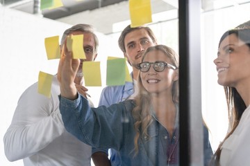 Business people meeting at office and use post it notes to share idea. Brainstorming concept. Sticky note on glass wall.