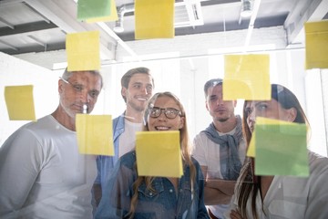 Business people meeting at office and use post it notes to share idea. Brainstorming concept. Sticky note on glass wall.