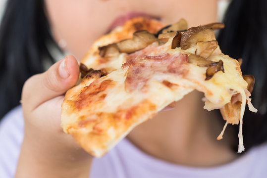 mmm, so delicious!, i recommend eat this delicious pizza!, little asia girl hold the pizza piece in his hand, enjoys nice taste, wants to eat, positive woman with junk food, people and eating.