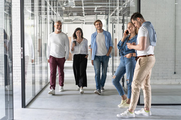 Obraz premium On the way to business meeting. Full length of young modern people in smart casual wear having a discussion while walking through the office