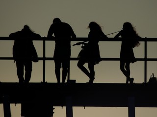 Silhouettes of people fishing from a pier