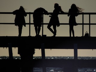 Silhouettes of people standing on a pier