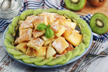 Austrian dessert Kaiserschmarrn served with sugar powder and kiwi fruit
