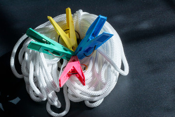 Colored clothespins on a clothesline on a black background.