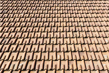 Red ceramic tile roof texture. Vintage old house rooftop background. Countryside architecture design. Dirty weathered tiled roof surface.