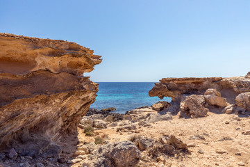 Fototapeta na wymiar Small hidden rocky cove off the coast of the Ibiza island. Balearic Islands, Spain