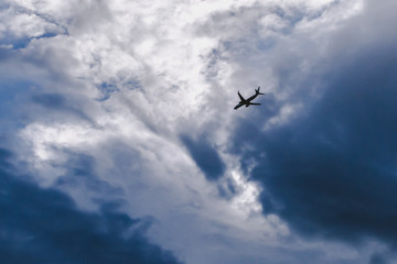 airplane flying dark blue white cloudy background