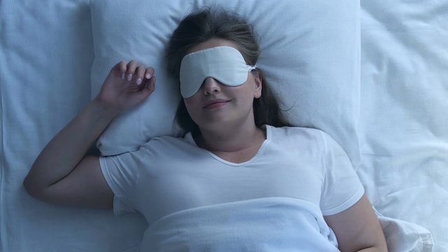 Excited plump woman smiling while asleep, enjoying pleasant dream, top view