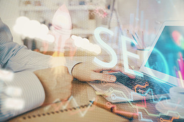 Double exposure of seo icon with man working on computer on background. Concept of search engine optimization.