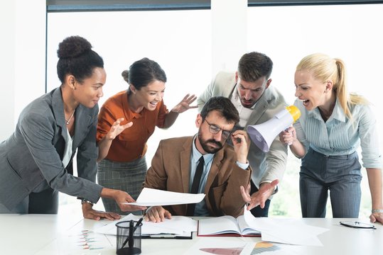 Colleagues screaming at businessman in office