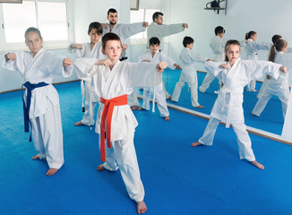 Fototapeta na wymiar Young children training karate kicks with master during karate class.