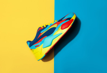 Multicolor sport shoes on yellow background with shadows