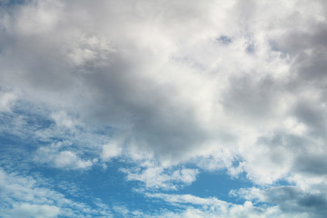 Blue bright sky with clouds, natural beautiful background. Soft daylight. Stock photo with empty space for text and design. 